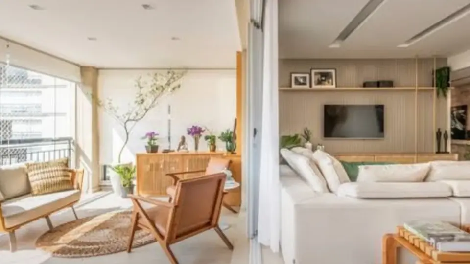 Imagem ilustrativa: sala integrada à varanda, com marcenaria clara, poltrona de couro e sofá branco